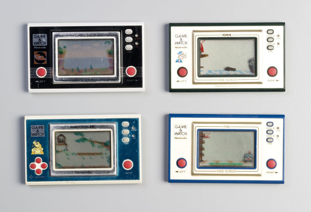 Four Nintendo Game and Watch electronic games. Each consists of a rectangular console with plastic casing and metallic front and an LCD display screen with permanent graphics incorporated. The LCD characters move through this display. The control buttons are red and there is a battery casing at the back. Decorative transfers. No packaging. The console is designed to be held comfortably in both hands and operated with the game controls under the thumbs.